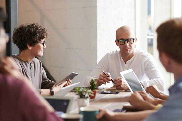 A team of individuals collaborating on a project using laptops at a table.