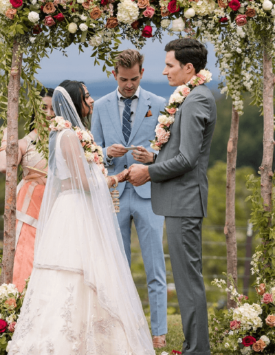 Newlyweds exchanging vows in a romantic outdoor ceremony surrounded by flowers.